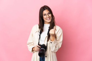 Pembe arka planda izole edilmiş Brezilyalı genç bir kız para hareketi yapıyor.