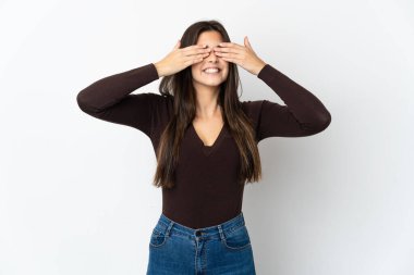 Genç Brezilyalı kız beyaz arka planda izole edilmiş gözleri elleriyle kaplıyor ve gülümsüyor.