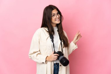 Genç fotoğrafçı Brezilyalı kız pembe arka planda izole edilmiş.