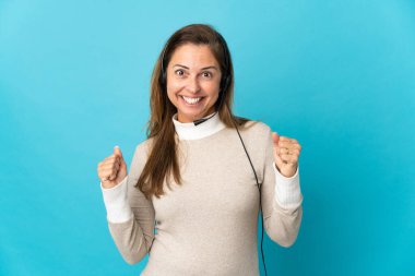 Soyutlanmış mavi arka planda genç bir pazarlamacı kadın galibiyeti kutluyor.