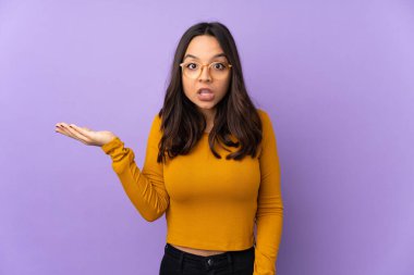 Mor arka planda izole edilmiş genç melez kadın şüpheli hareketler yapıyor.