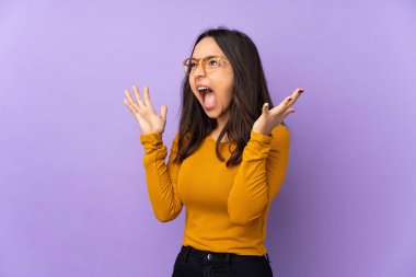 Mor arka planda yalıtılmış, sürpriz bir yüz ifadesi olan genç melez bir kadın.