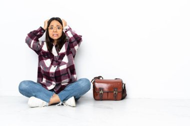 Genç bayan öğrenci yerde oturmuş gergin hareketler yapıyor.