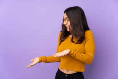 Mor arka planda yalıtılmış, sürpriz bir yüz ifadesi olan genç melez bir kadın.