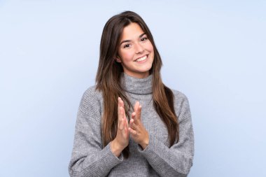 İzole edilmiş mavi arka planda genç Brezilyalı kız bir konferanstan sonra alkışlıyor.