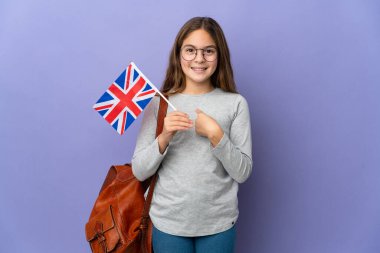 Çocuk, Birleşik Krallık bayrağını yalıtılmış bir arkaplanda sürpriz bir yüz ifadesiyle tutuyor