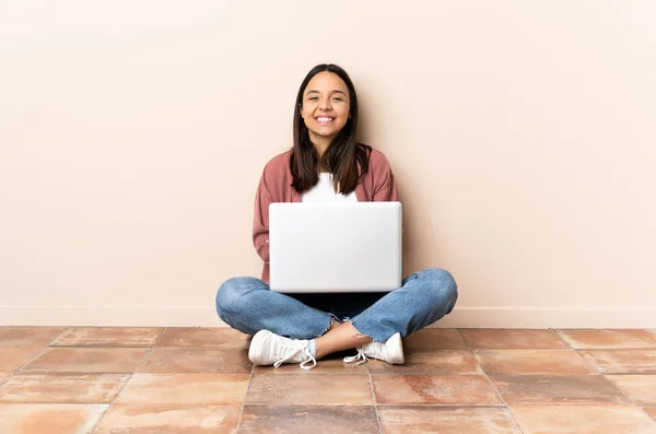 年轻的混血女子 手持笔记本电脑坐在地板上笑着 — 图库照片
