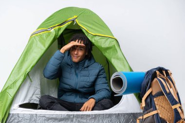 Genç Afro-Amerikan bir adam kamp yeşil çadırında uzaklardan bir şeye bakıyor.