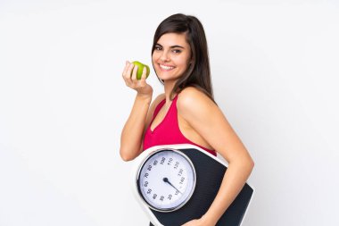 Tartı makinesi ve elmasıyla izole edilmiş beyaz arka planı olan genç bir kadın.