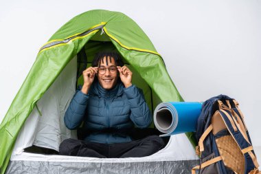 Genç Afro-Amerikan bir adam kamp yeşil çadırında gözlüklü ve şaşırmış.