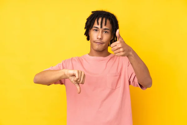 Mladý Afroameričan Izolovaný Žlutém Pozadí Dělá Dobré Znamení Nerozhodnuto Mezi — Stock fotografie