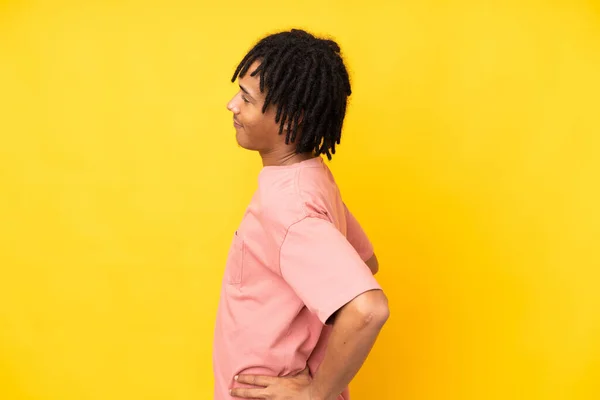若いアフリカ系アメリカ人の男性は 努力をしたために腰痛に苦しんでいる黄色の背景に隔離されました — ストック写真