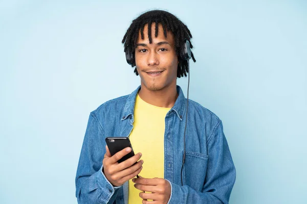 Jonge Afrikaanse Amerikaanse Man Geïsoleerd Blauwe Achtergrond Luisteren Muziek Met — Stockfoto