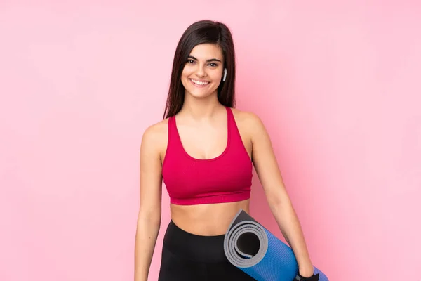 年轻的女运动员 穿着一条垫子 面带微笑地穿过孤立的粉色背景 — 图库照片