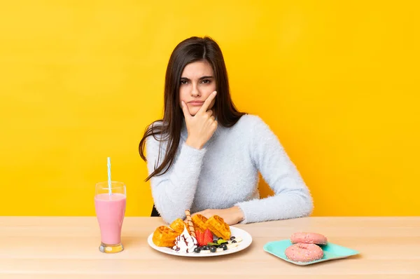 Jonge Vrouw Eten Wafels Milkshake Een Tabel Geïsoleerde Gele Achtergrond — Stockfoto