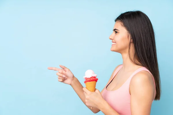 Jonge Vrouw Met Een Cornet Ijs Geïsoleerde Blauwe Achtergrond Wijzend — Stockfoto