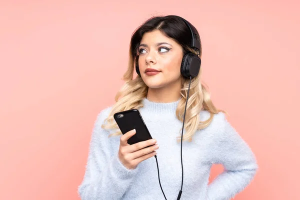 Adolescente Chica Aislado Rosa Fondo Escuchar Música Con Móvil Pensando —  Fotos de Stock