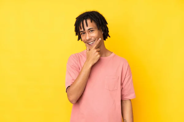 黄色の背景に孤立した若いアフリカ系アメリカ人の男が微笑む — ストック写真