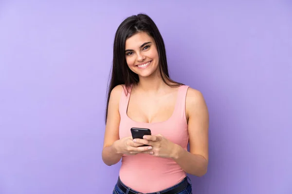 来自紫色背景的年轻女子用手机传送讯息 — 图库照片