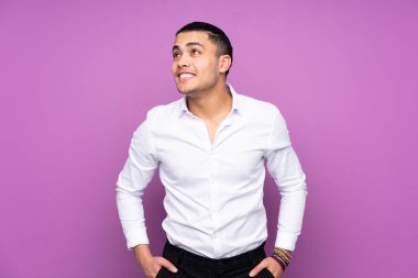 Asyalı yakışıklı bir adam mavi arka planda izole edilmiş, yukarı bakarken bir fikir düşünüyor.