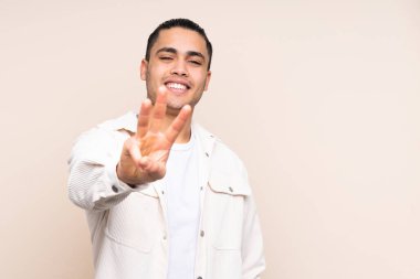 Asyalı yakışıklı adam izole olmuş mutlu ve parmaklarıyla üçe kadar sayıyor.