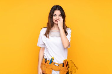 Sarı arka planda izole edilmiş genç elektrikçi kadın gergin ve korkmuş.