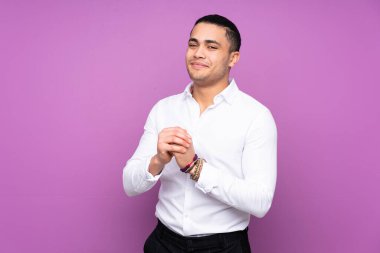 Asyalı yakışıklı adam mavi arka planda yalnız gülüyor.