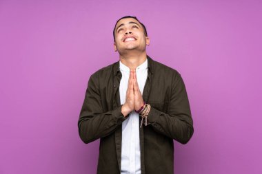 Asyalı yakışıklı adam mavi arka planda tek başına avuç içlerini bir arada tutuyor. İnsan bir şey ister.