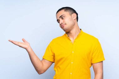 Asyalı yakışıklı adam tecrit edilmiş arka planda, kopyalama alanını şüpheyle tutuyor