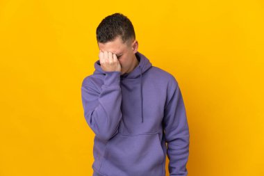 Sarı arka planda başağrısı olan genç beyaz bir adam izole edilmiş.