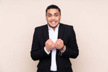 Asyalı iş adamı bej arka planda izole edilmiş zaferi kutluyor.