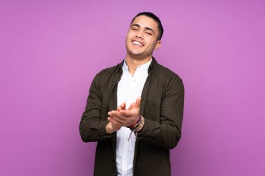 Asyalı yakışıklı adam mavi arka planda izole edilmiş bir konferansta sunumdan sonra alkışlıyor.