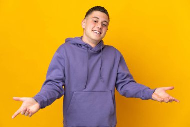 Sarı arka planda izole edilmiş genç beyaz adam mutlu ve gülümsüyor.