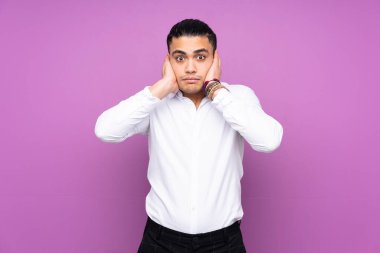 Asyalı yakışıklı adam mavi arka planda izole edilmiş hayal kırıklığına uğramış ve kulaklarını kapatmış.