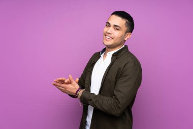 Asyalı yakışıklı adam, mavi arka planda tek başına alkışlıyor.