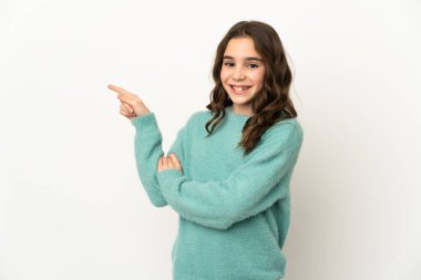 Beyaz arka planda izole edilmiş küçük beyaz kız parmağını yana doğru gösteriyor.