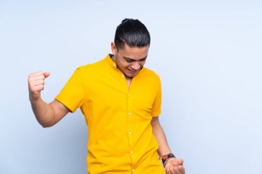 Asyalı yakışıklı adam, izole edilmiş arka planda zaferi kutluyor.