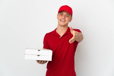 İş üniformalı bir pizzacı beyaz arka planda izole edilmiş pizza kutularını topluyor ve iyi bir anlaşma için el sıkışıyor.