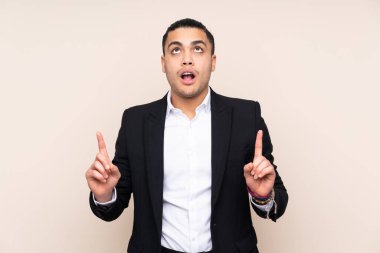 Asyalı iş adamı bej arka planda izole edilmiş işaret parmağıyla işaret etmek harika bir fikir.