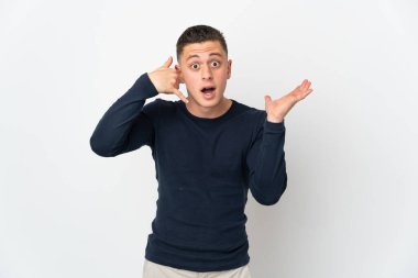 Beyaz arka planda izole edilmiş genç beyaz bir adam telefon jesti yapıyor ve şüpheli.