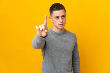 Sarı arka planda izole edilmiş beyaz bir adam ciddi bir ifadeye sahip birini sayıyor.