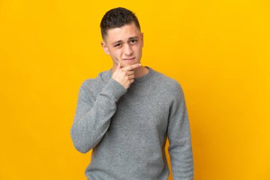 Sarı arka planda izole edilmiş genç beyaz adamın şüpheleri var.