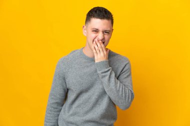 Sarı arka planda izole edilmiş genç beyaz adam mutlu ve gülümsüyor.