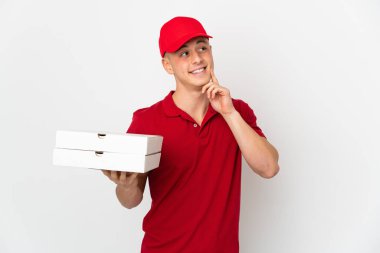 İş üniformalı bir pizzacı beyaz arka planda izole edilmiş pizza kutularını topluyor.