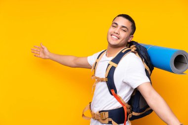 Tecrit edilmiş arka planda büyük bir sırt çantası olan genç dağcı.