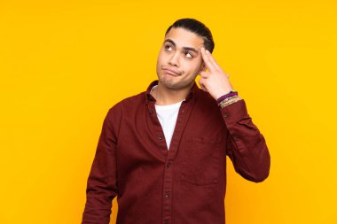 Asyalı yakışıklı adam sarı arka planda izole edilmiş ön tarafı işaret ediyor ve gülümsüyor.