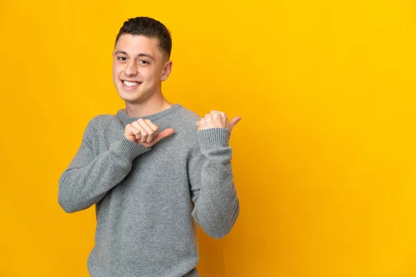 Hombre Joven Caucásico Aislado Sobre Fondo Amarillo Apuntando Hacia Lado — Foto de Stock