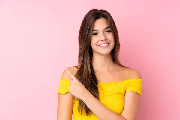 Menina Brasileira Adolescente Sobre Fundo Rosa Isolado Apontando Para Lado — Fotografia de Stock