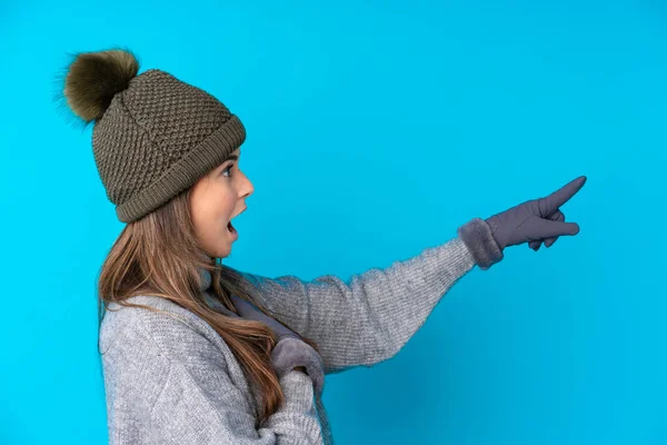 Menina Adolescente Com Chapéu Inverno Sobre Fundo Azul Isolado Apontando — Fotografia de Stock