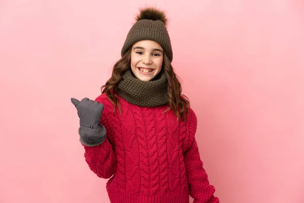 모자를 분홍색 배경에 고립된 소녀가 제품을 제공하는 측면을 가리키고 — 스톡 사진